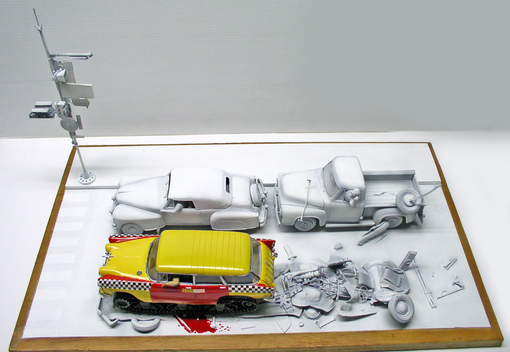 Diorama de maquettes de voitures grises et un taxi jaune accidenté entouré de débris épars