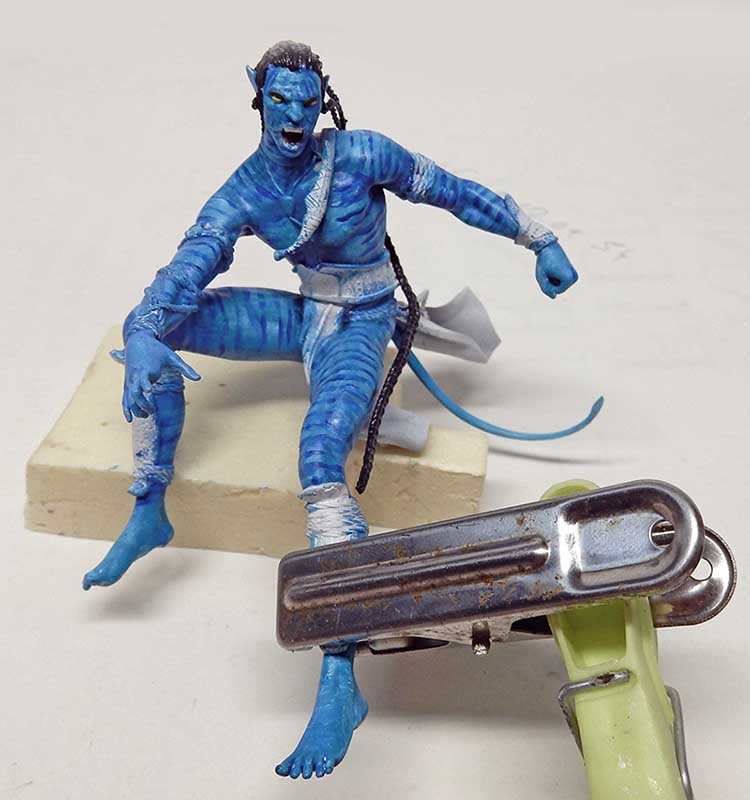 Figurine Na'vi bleue d'Avatar 2 en cours de peinture posée sur un socle de mousse