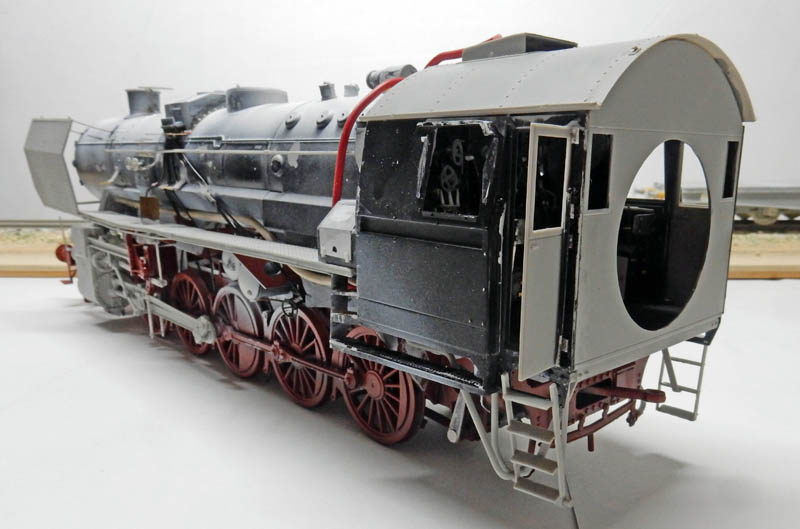 Maquette de locomotive à vapeur BR52 en construction, cabine grise et roues rouges