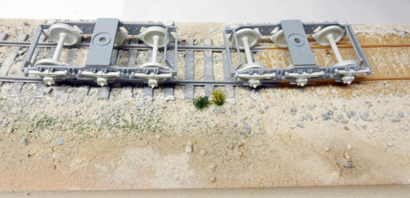 Châssis et essieux gris de la maquette BR52 posés sur une voie ferrée miniature