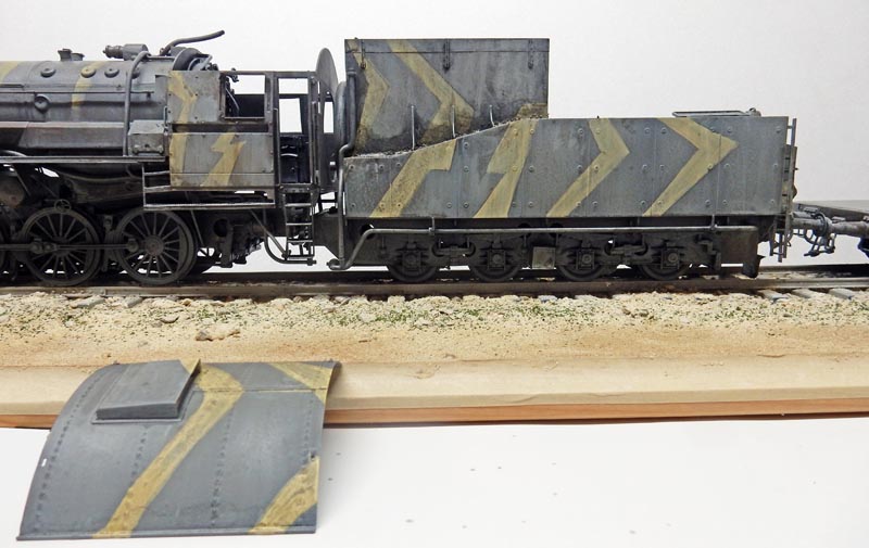 Maquette de locomotive à vapeur BR52 avec tender camouflé à chevrons jaunes sur voie ferrée