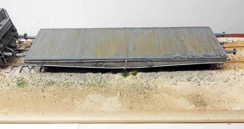 Maquette de wagon plat à plancher en bois gris vieilli posé sur un diorama de voie ferrée