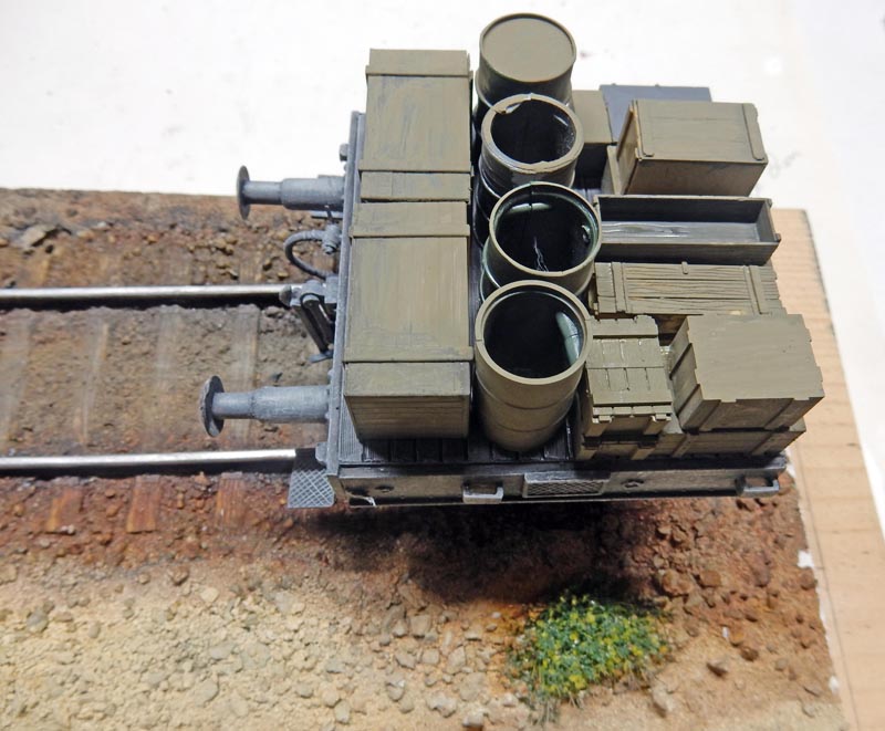 Maquette de wagon plat BR52 chargé de fûts et caisses sur voie ferrée