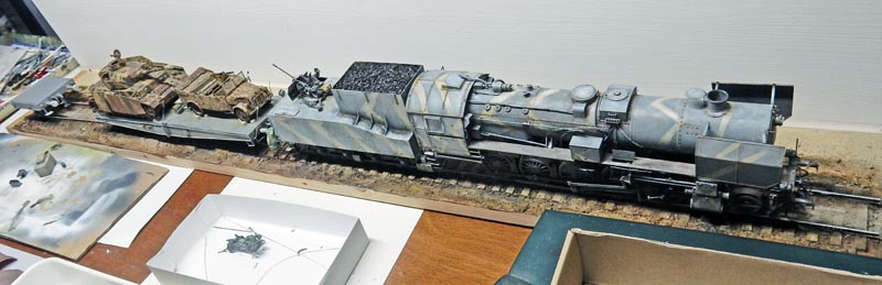 Maquette de locomotive à vapeur BR52 camouflée avec wagon chargé de véhicules militaires sur diorama