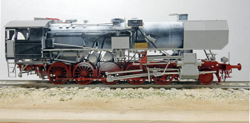 Maquette de locomotive à vapeur BR52 vue de profil, châssis rouge et chaudière partiellement peinte