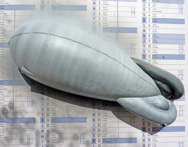 Maquette d'enveloppe de ballon dirigeable gris posée sur un calendrier, avec empennage arrière