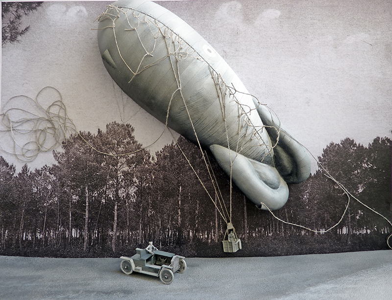 Maquette de ballon dirigeable d'observation 1917 avec nacelle et véhicule ancien devant une forêt de pins