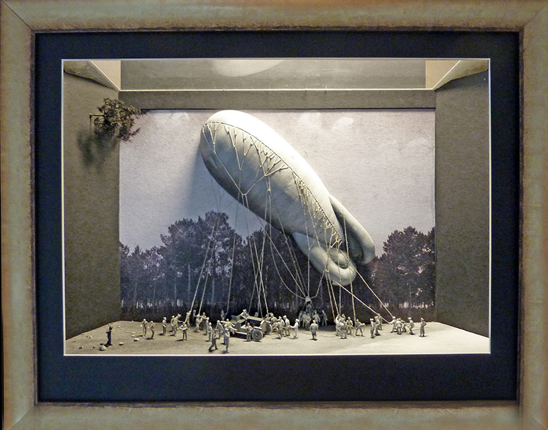 Diorama encadré d'un ballon dirigeable de 1917 manœuvré au sol par des soldats devant une forêt