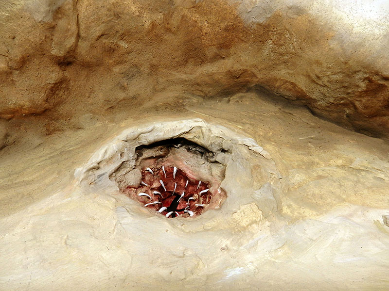 Détail du décor de roche sculptée montrant une gueule rouge aux dents pointues