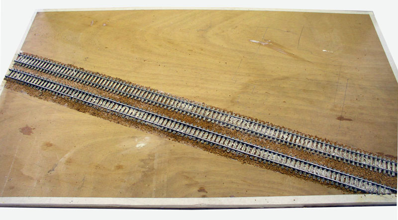 Deux voies ferrées parallèles posées sur ballast collé sur une plaque de bois