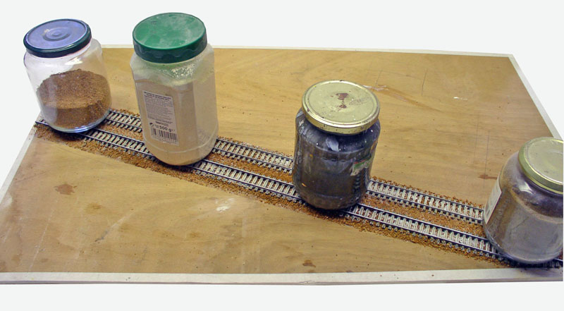 Pots de ballast et matériaux le long d'une voie ferrée miniature en construction sur planche