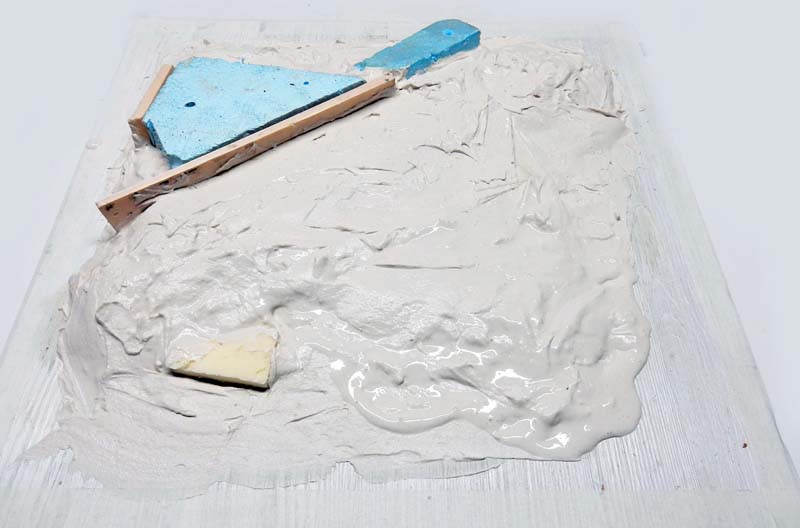 Enduit de modelage étalé sur socle en bois avec mousse bleue et polystyrène