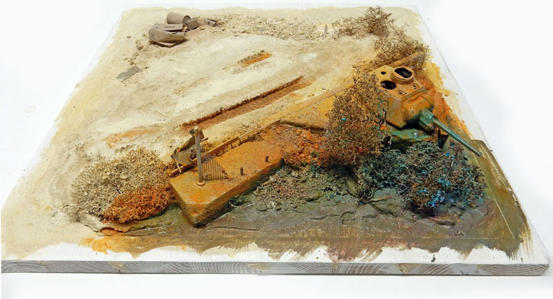 Diorama désertique en cours de décor, socle sablonneux, végétation sèche, tourelle et épave enterrées
