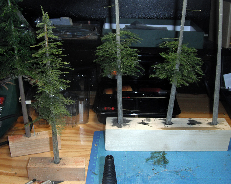 Arbres miniatures de sapins en cours de fabrication fixés sur des socles en bois