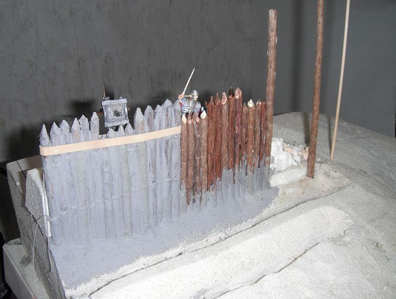 Maquette d'une palissade de camp romain avec figurine de légionnaire et enseigne en construction