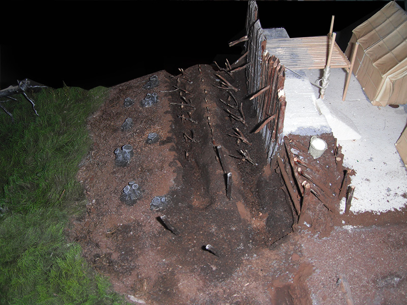 Maquette de fortification romaine avec talus, pieux défensifs et palissade de bois protégeant le rempart
