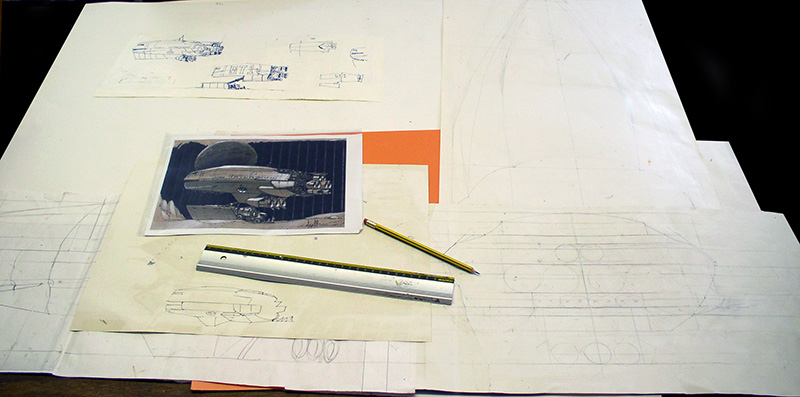 Croquis préparatoires d'un cargo spatial avec photo de référence, crayon et règle sur la table