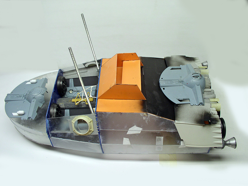 Maquette de cargo spatial en construction avec structure orange, antennes métalliques et détails gris
