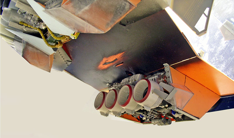 Maquette de cargo spatial montrant les tuyères de propulsion et le fuselage orange patiné