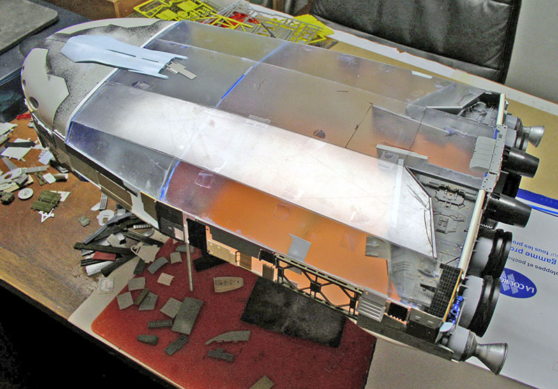 Maquette de cargo spatial en construction sur un plan de travail avec pièces et tuyères