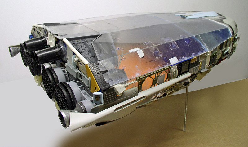 Maquette de cargo spatial avec verrière transparente, tuyères et détails mécaniques, posée sur support