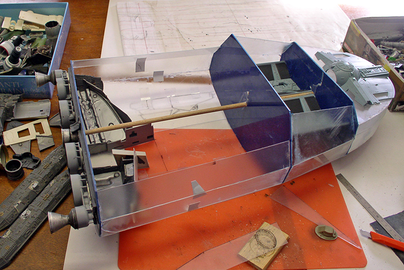 Maquette de cargo spatial en construction sur plan, structure transparente et pièces détaillées sur l'établi