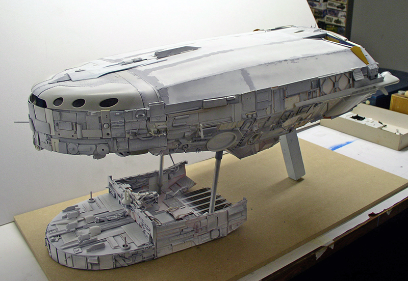 Maquette de cargo spatial en cours de montage posée sur un support en bois