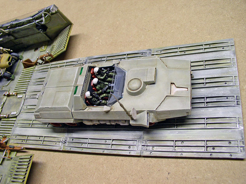 Maquette de véhicule blindé spatial avec figurines en cabine ouverte sur plateforme à rails
