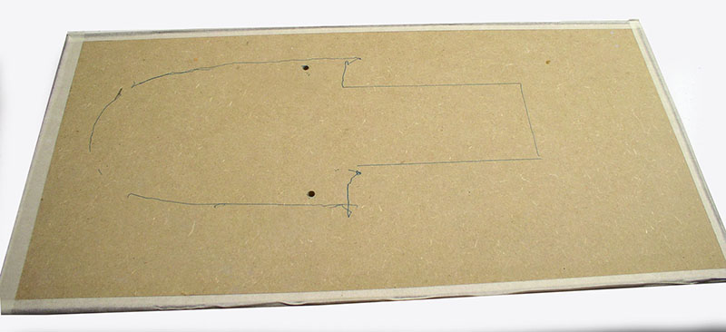 Plaque de carton bois avec tracé au crayon de la silhouette du cargo spatial