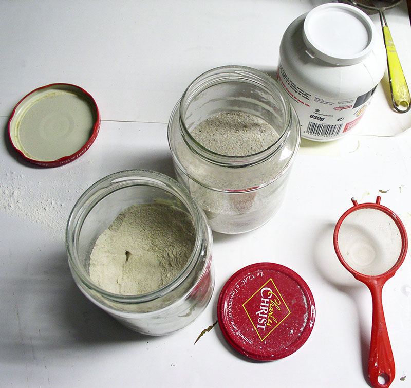 Bocaux en verre remplis de poudre et sable de tamisage avec petite passoire rouge