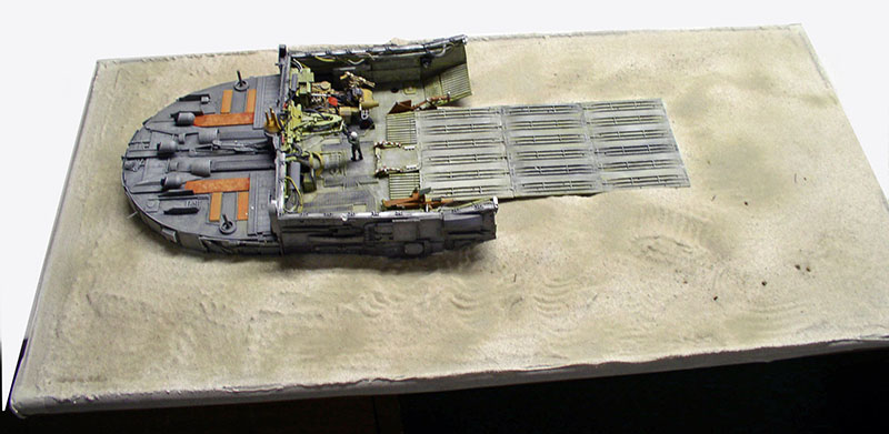 Maquette de cargo spatial posé sur un diorama de sol désertique avec passerelle et figurines