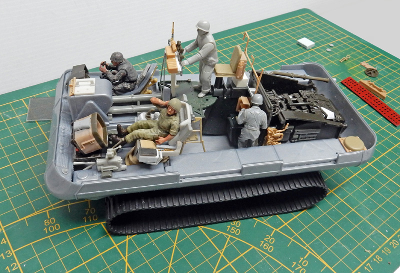 Diorama de véhicule chenillé militaire en cours de montage avec figurines de soldats sur tapis de découpe