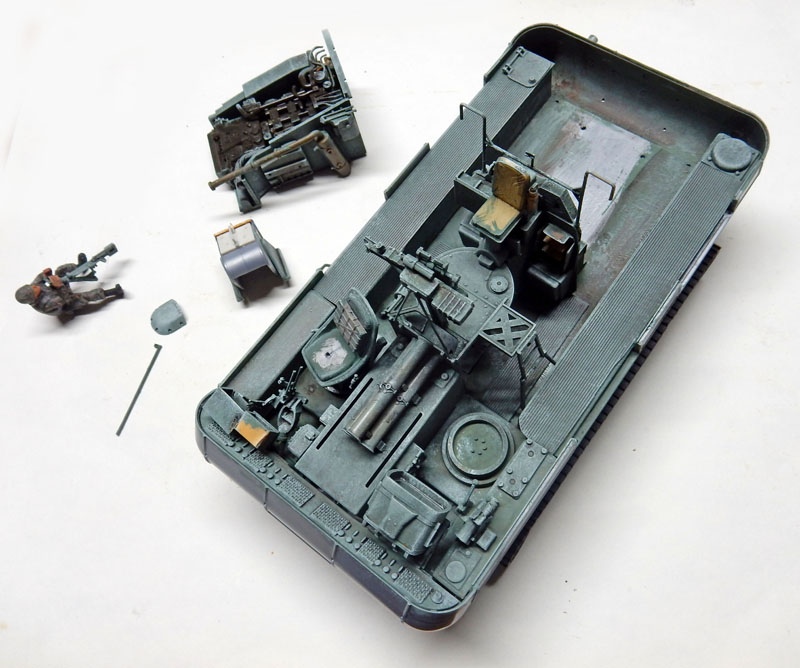 Maquette de châssis blindé gris avec intérieur détaillé, moteur et figurine en cours d'assemblage