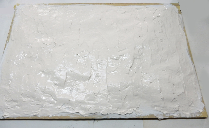 Couche d'enduit blanc texturé appliquée sur une plaque de base de diorama