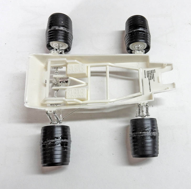 Châssis blanc de maquette automobile avec quatre roues noires et suspensions chromées vu de dessus