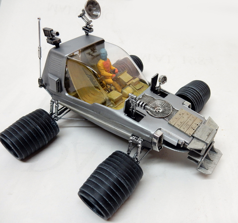 Maquette de véhicule lunaire argenté avec pilote en combinaison orange sous bulle transparente