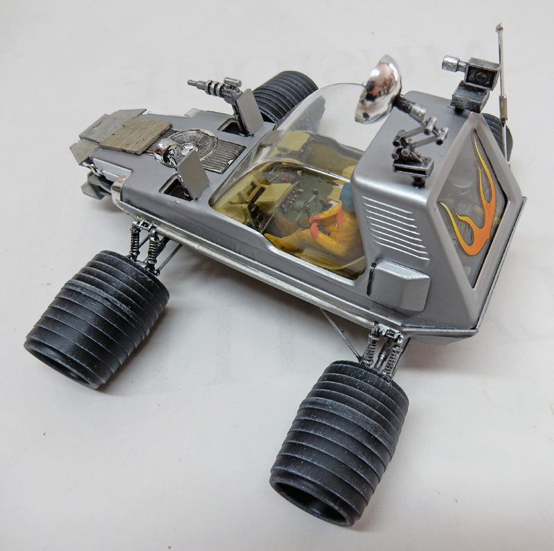 Maquette de véhicule lunaire futuriste argenté avec grosses roues nervurées et flammes orange peintes