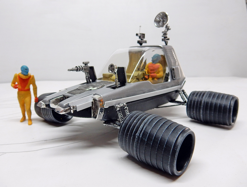 Maquette de véhicule lunaire futuriste argenté avec figurines d'astronautes dans un diorama