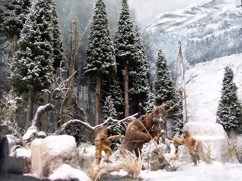 Diorama enneigé de chasseurs affrontant un ours brun dans une forêt de sapins montagneuse