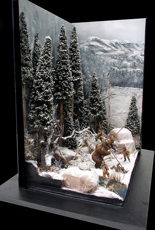 Diorama d'une chasse à l'ours en forêt enneigée avec sapins, montagnes et chasseurs préhistoriques