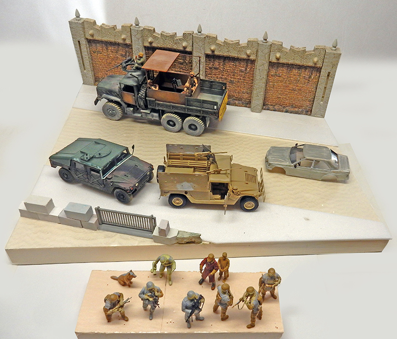 Maquettes militaires d'un check-point : camion, Humvee, soldats et figurines devant un mur de briques