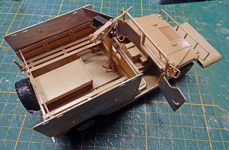 Maquette de véhicule militaire beige avec mitrailleuse, en cours d'assemblage sur tapis de découpe