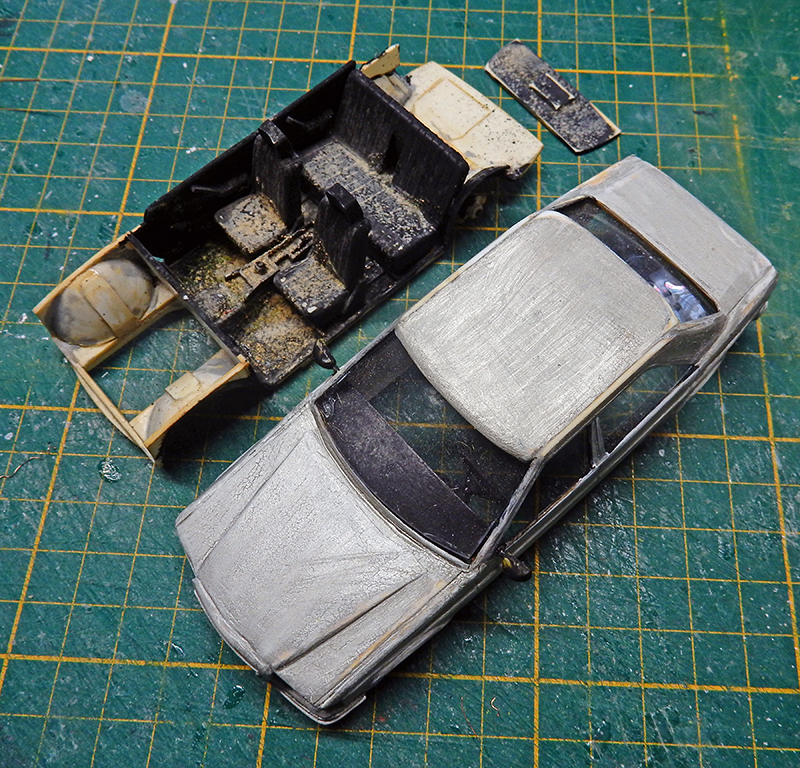 Carrosserie de voiture maquette grise vieillie et châssis séparé sur tapis de découpe vert