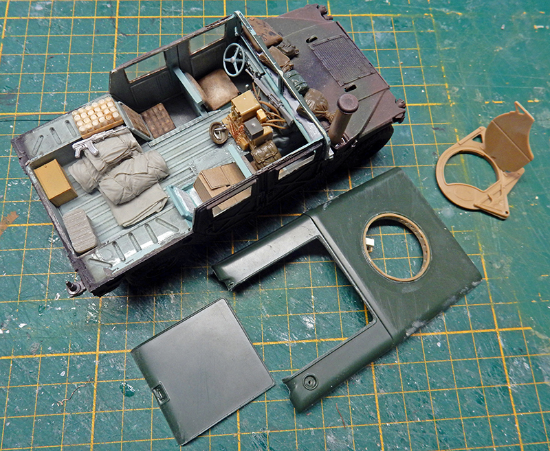 Maquette de véhicule militaire en cours d'assemblage avec intérieur détaillé et pièces de carrosserie sur tapis de découpe