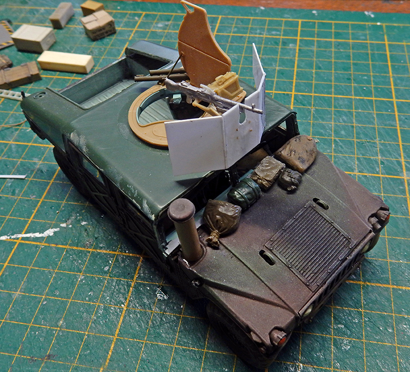 Maquette de véhicule blindé militaire vert en construction avec mitrailleuse et équipements sur tapis de découpe