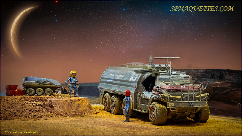 Diorama de colonisation martienne avec gros véhicule tout-terrain, astronautes et croissant de planète au ciel