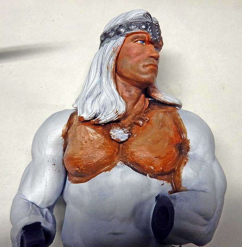 Buste de Conan en cours de peinture, carnation du torse et bandeau argenté appliqués sur figurine grise