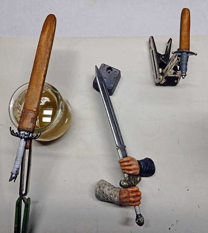 Mains de figurine peintes tenant une épée en cours d'assemblage avec outils de maquettiste