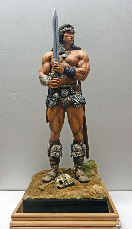 Figurine peinte de Conan le barbare tenant son épée, debout sur socle avec crâne