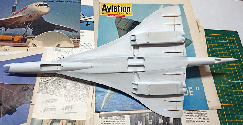 Maquette du Concorde en apprêt gris vue de dessus posée sur documentation aéronautique
